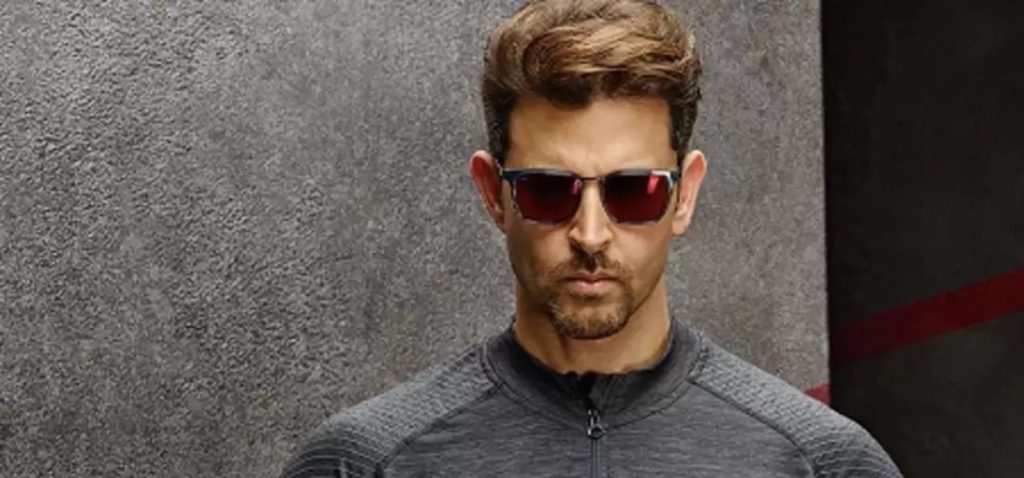 Hrithik Roshan wearing red-mirrored sporty sunglasses with a dark grey activewear jacket.