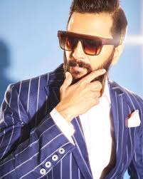 Riteish Deshmukh in a pinstripe suit wearing oversized square sunglasses with a gradient tint.